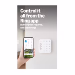 Ring Alarm keypad mounted on a wall with the Ring app open on a phone