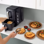 Ninja DoubleStack 2-Basket Air Fryer SL201C with the lower basket open and fries being served onto plates of chicken and vegetables