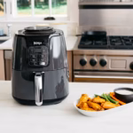 Ninja AF101C air fryer beside a plate of chicken wings and vegetables