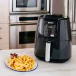 Ninja AF101C air fryer on a counter beside a plate of cooked French fries