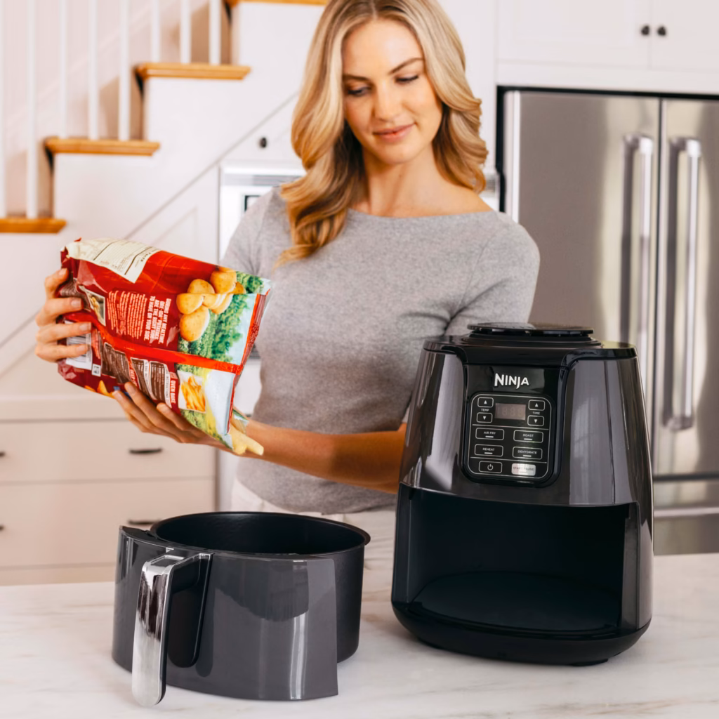 Ninja AF101C air fryer being loaded with frozen fries from the bag