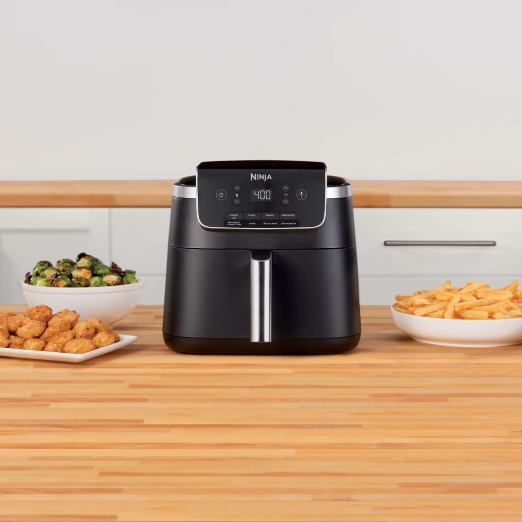 Ninja AF141C air fryer on a counter beside bowls of cooked food