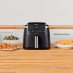 Ninja AF141C air fryer on a counter beside bowls of cooked food