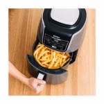 Ninja AF161C air fryer basket pulled open with a full load of crisp French fries