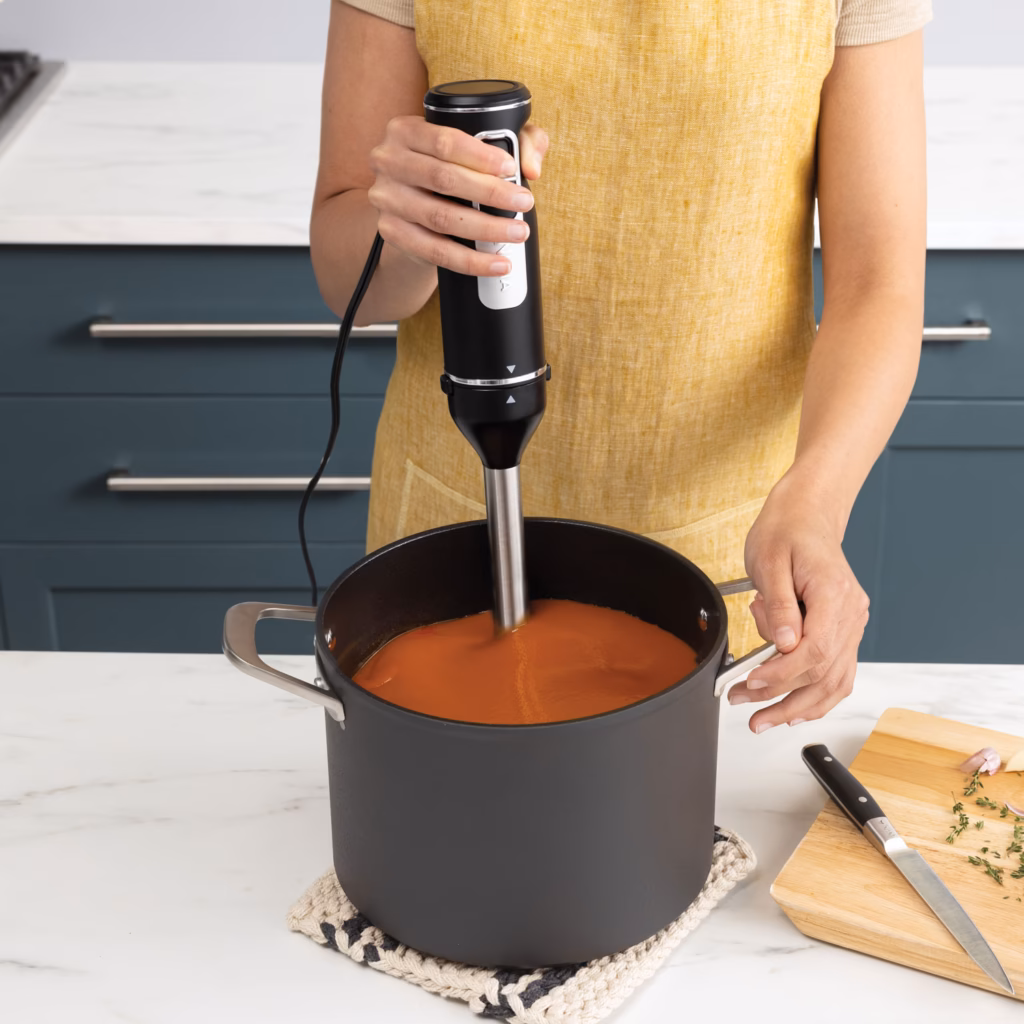 Ninja CI100C immersion blending arm pureeing tomato soup in a deep pot