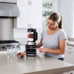 Ninja HB150C blending a berry smoothie in its glass pitcher in a bright kitchen
