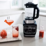 Ninja HB150C blender on a kitchen counter beside infused drinks and a cocktail