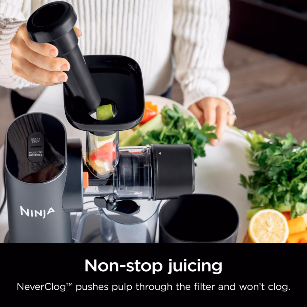 Ninja NeverClog Cold Press Juicer JC151C feeding leafy greens into the chute