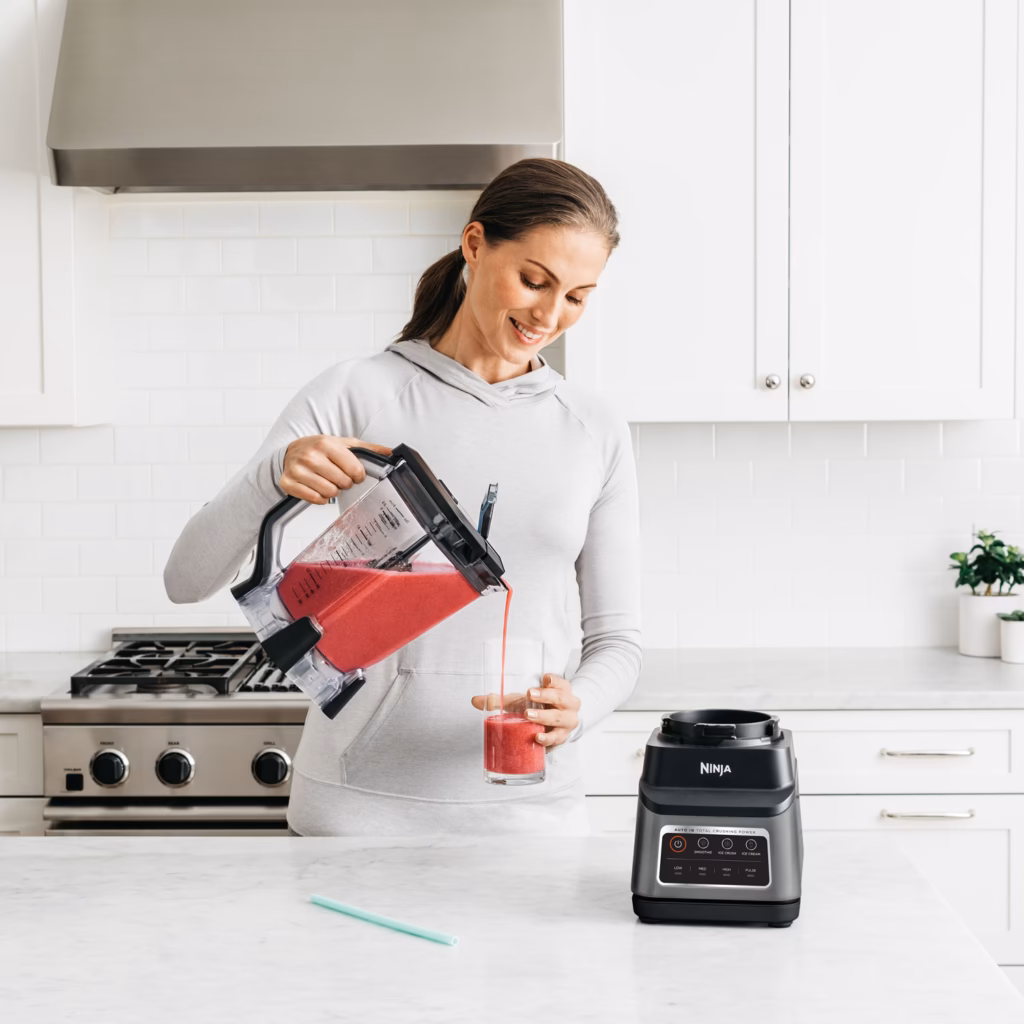 Pouring a smoothie from the Ninja BN701C 72 oz Total Crushing pitcher into a glass