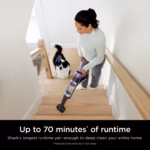 Shark PowerDetect IP3251C cordless stick vacuum being used on carpeted stairs with a dog nearby